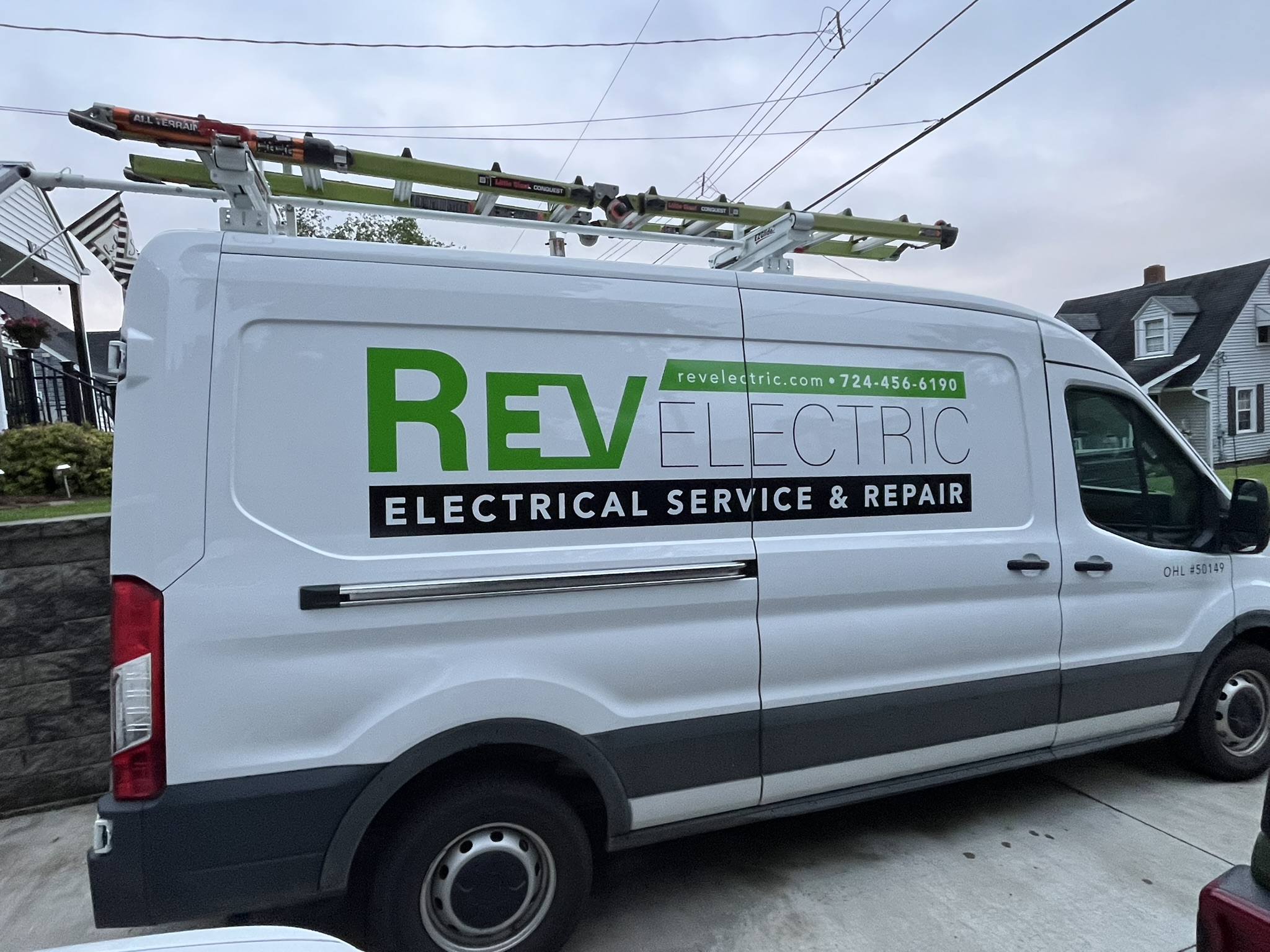 White Rev Electric service van with ladders on roof and 'Electrical Service & Repair' signage