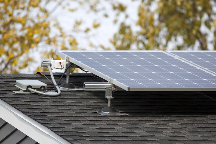 Solar panels mounted on a shingled residential roof with mounting hardware and electrical connections