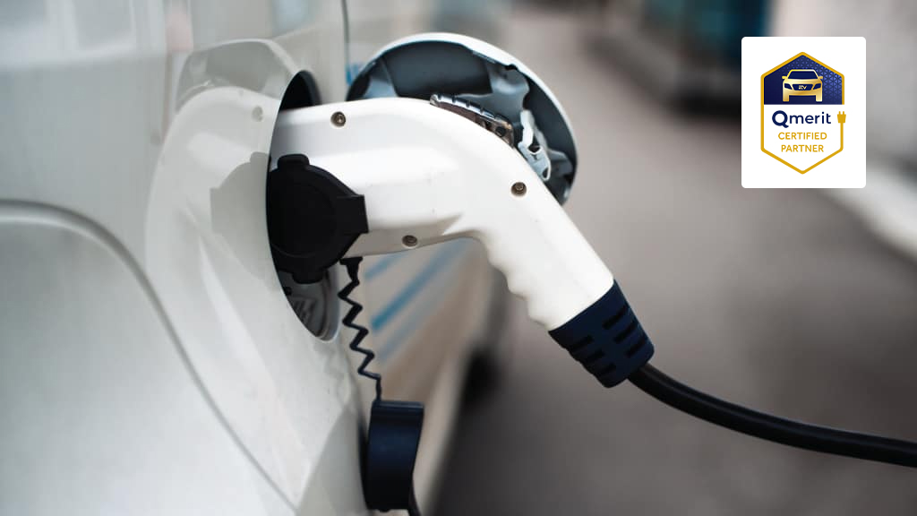 EV charging plug connected to a white car's charging port, Qmerit certified partner badge